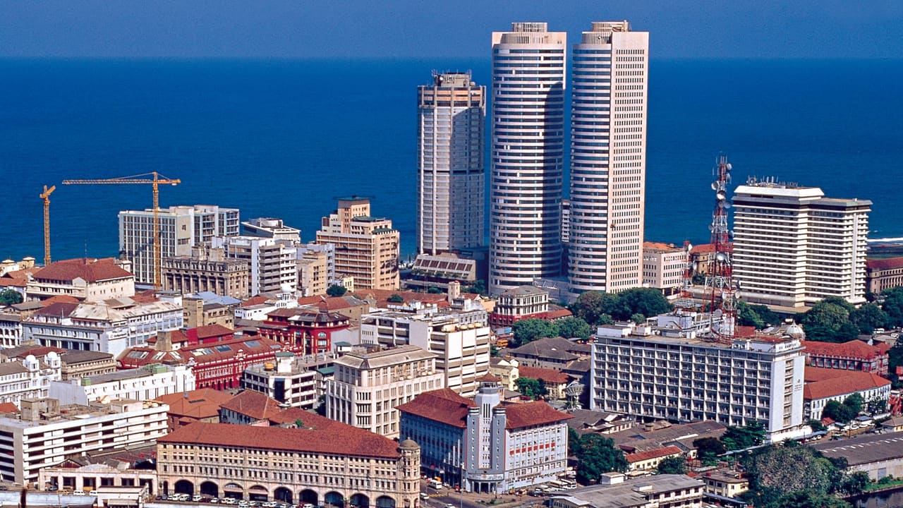 Colombo from above, high-rise towers over the red-tiled roofs of the older city with the sea beyond.