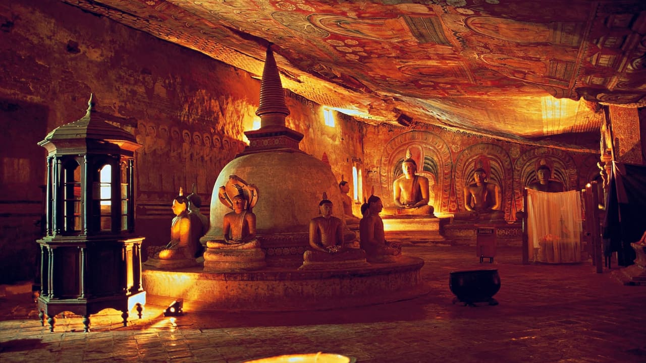 The interior of a Dambulla cave temple, its ceiling painted to the curve of the rock above a dagoba and rows of Buddha images.