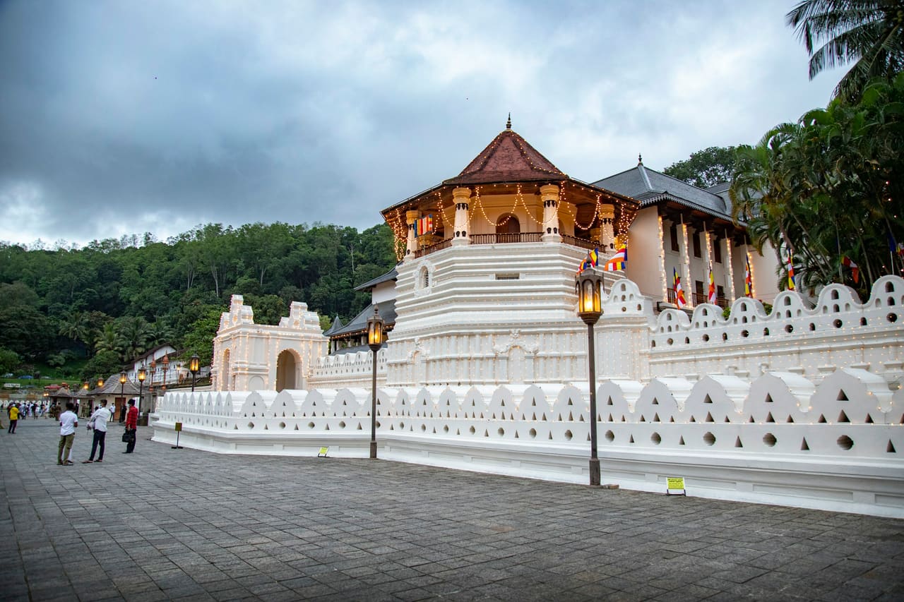 The Temple of the Sacred Tooth Relic in Kandy, its white walls and tiled roofs along the lake.
